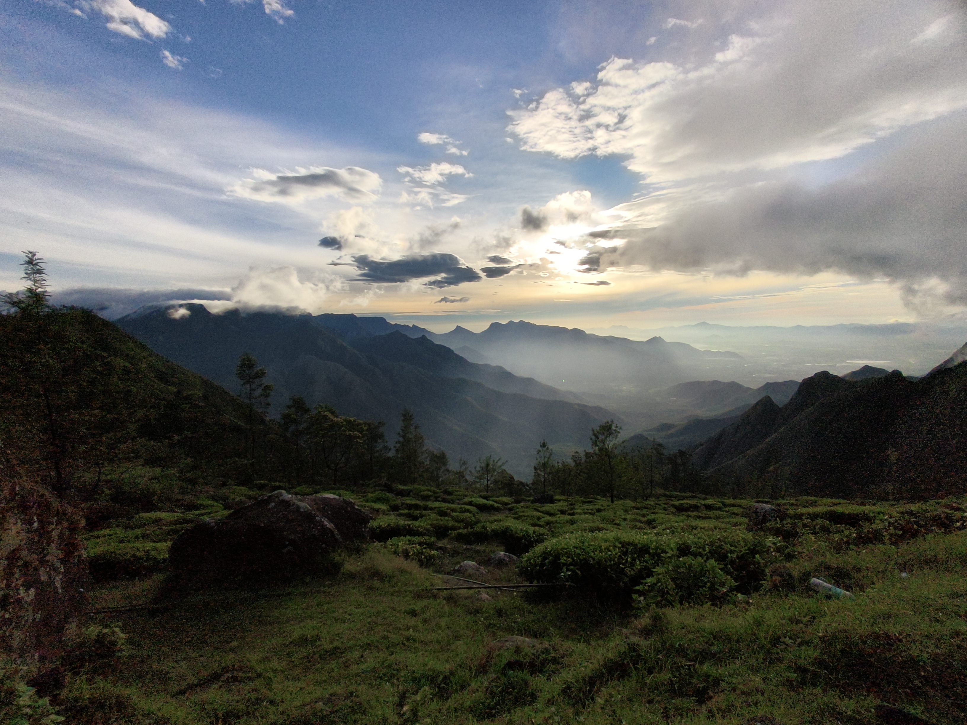 Kolukkumalai tea plantations with misty green hills and cloudy sky